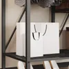 Two white shopping bags on a shelf in a closet. Produktbild-Vorschau