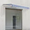 A retractable awning with blue and white stripes is mounted above a large window on a concrete wall. Náhled obrázku produktu
