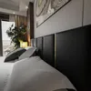 A close-up view of a bed with a black upholstered headboard and pillows. Produktbild-Vorschau