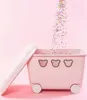 A pink toy box with bear faces and wheels, with colorful confetti falling into it. Podgląd zdjęcia produktu