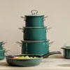 A set of teal-colored cookware, including pots and a frying pan, is neatly arranged on a light-colored surface. Produktbild-Vorschau