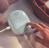 A hand is pressing a button on a Philips Avent electronic breast pump. Produktbild-Vorschau