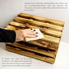 A hand is wiping a wooden crate with a cloth, with text providing instructions. Produktbild-Vorschau
