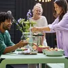 People are enjoying a meal outdoors at a table. Produktbild-Vorschau