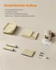 A collection of parts for a cat tree, including a bed, platforms, and scratching posts, laid out on a plain background. A cat is looking at an instruction manual. Produktbild-Vorschau