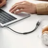 A person's hands are using a laptop, with an audio splitter cable connecting to the laptop and then splitting into two cables for headphones. Podgląd zdjęcia produktu