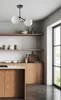 A modern kitchen with wooden cabinets and shelves, featuring a black chandelier with two white glass globes. Produktbild-Vorschau