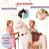 Two young girls interacting with a large white toy horse, with inset images showing accessories and other toy horses. Produktbild-Vorschau