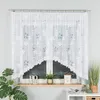 A white lace curtain with a floral pattern hangs over a window. Decorative items are placed on the windowsill below. Náhled obrázku produktu