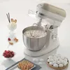 A vintage-style kitchen mixer with a bowl of whipped cream and various dessert items arranged around it. Náhled obrázku produktu