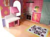A dollhouse kitchen with various furniture pieces and a rug on the floor. Voir les images du produit