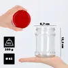A hand holds a red lid over a clear glass jar, with dimensions and weight information displayed. Produktbild-Vorschau