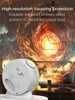 A white projector is shown in the foreground, projecting a swirling, fiery nebula onto a wall in the background. The scene is set in a living room with furniture visible. Náhled obrázku produktu