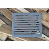 A cast iron grate is placed on a pile of firewood. Voir les images du produit