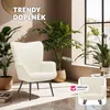 A cream-colored armchair is showcased in a well-lit room with plants and a window. Náhled obrázku produktu