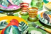 A tropical-themed table setting with plates, glasses, and fruit. Anteprima dell’immagine prodotto