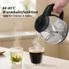 A hand is pouring hot water from a glass kettle into two cups, one with tea and one with coffee. Steam is rising from the cups. Produktbild-Vorschau