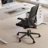 An office chair is shown in a well-lit office environment, placed on a wooden floor next to a desk. Produktbild-Vorschau