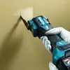 A person wearing gloves is using a cordless oscillating multi-tool to cut a square opening in a wall. Produktbild-Vorschau
