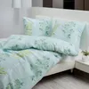 A neatly made bed with light blue bedding featuring a green leaf pattern. Produktbild-Vorschau