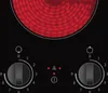 A close-up view of a black glass ceramic cooktop with two heating elements and control knobs. Produktbild-Vorschau