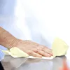 A hand is wiping a surface with a yellow paper towel. Podgląd zdjęcia produktu