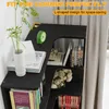 A black corner bookshelf filled with books and decorative items, placed next to a window with curtains. Voir les images du produit