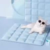 A white cat wearing sunglasses is lying on a light blue cooling mat. Produktbild-Vorschau