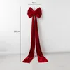 A large red velvet bow with long streamers is hanging on a white wall. Podgląd zdjęcia produktu