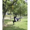 Two people relaxing on a swing hanging from a tree in a park. Anteprima dell’immagine prodotto