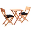 A wooden folding table and two chairs with black cushions, set against a white background. Produktbild-Vorschau