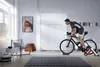 A man is riding a stationary bicycle in a modern living room. Produktbild-Vorschau