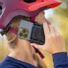 A person wearing a helmet and attaching a phone to it. Produktbild-Vorschau