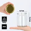 A hand holds a glass jar with a gold lid, and another hand holds a glass jar with dimensions indicated. Voir les images du produit