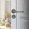 A close-up of a door handle and lock set on a door, with a blurred background of a room interior. Produktbild-Vorschau