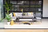 An outdoor seating area with a sofa, dining table, bench, and chairs, decorated with plants and cushions. Produktbild-Vorschau