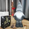 A Christmas-themed display featuring a gnome figure, gift bags, and decorative elements. Náhled obrázku produktu