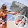 A woman on a beach holding a gray beach umbrella. Náhled obrázku produktu