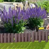 A person is installing a brown plastic garden border with a mallet next to purple flowers and rocks. Produktbild-Vorschau