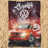 A blanket with a Volkswagen Golf GTI design is laid out on a sandy surface. Produktbild-Vorschau