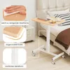 A laptop table with wheels is shown next to a bed, with close-up insets highlighting features. Produktbild-Vorschau