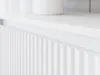 A close-up shot of a white fluted cabinet door with a white shelf above it. Náhled obrázku produktu