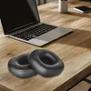 A laptop and two black headphone ear pads on a wooden desk. Produktbild-Vorschau