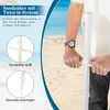 A person on a beach holding a white beach umbrella stand. Náhled obrázku produktu