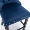 Close-up of a blue velvet bar stool seat and part of the backrest, showing the tufted detailing and nailhead trim. Produktbild-Vorschau