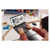 A person using a laptop on a glass table with a cup of tea and a mouse nearby. Produktbild-Vorschau