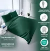 A dark green duvet cover and pillow set laid out on a bed in a modern bedroom setting, with promotional text and icons on the right side. Produktbild-Vorschau
