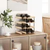 A wine rack filled with bottles sits on top of a cabinet, next to a vase with greenery and a small cup and saucer. Náhled obrázku produktu