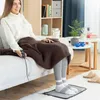 A woman is sitting on a couch, covered with a brown blanket, and her feet are placed on a gray heated mat on the floor. Náhled obrázku produktu
