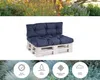 A dark blue pallet sofa cushion set on a white background, with a blurred garden scene above and foliage below. Voir les images du produit
